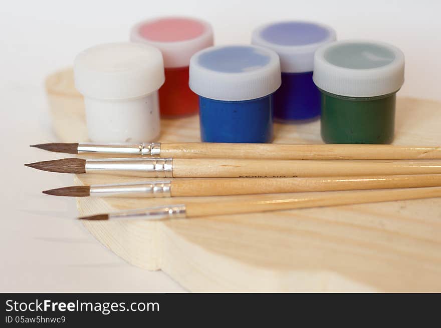 Brushes and acrylic paint on a wooden plank. Brushes and acrylic paint on a wooden plank.