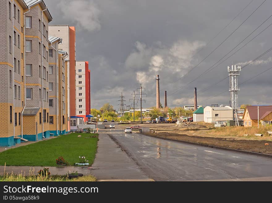 Street with houses, power lines against a cloudy sky. Street with houses, power lines against a cloudy sky.