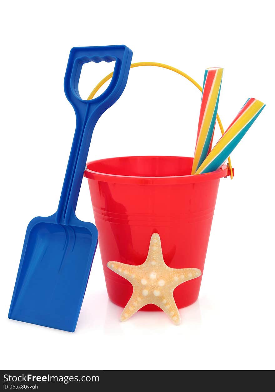 Bucket and spade plastic beach toy in red and blue with stick of rock and starfish over white background. Bucket and spade plastic beach toy in red and blue with stick of rock and starfish over white background.