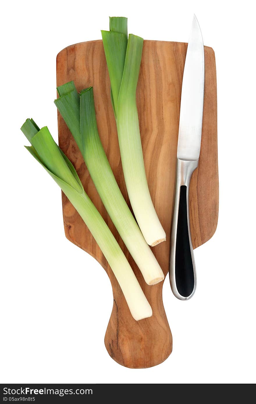 Leek vegetables on an olive wood chopping board with kitchen knife isolated over white background. Leek vegetables on an olive wood chopping board with kitchen knife isolated over white background.