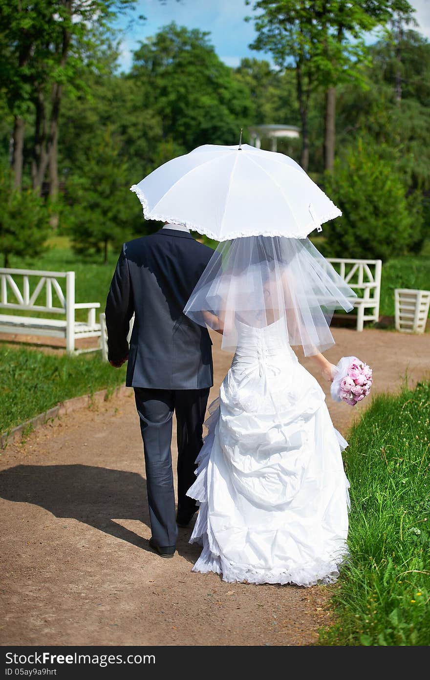 Happy bride and groom goes along the path