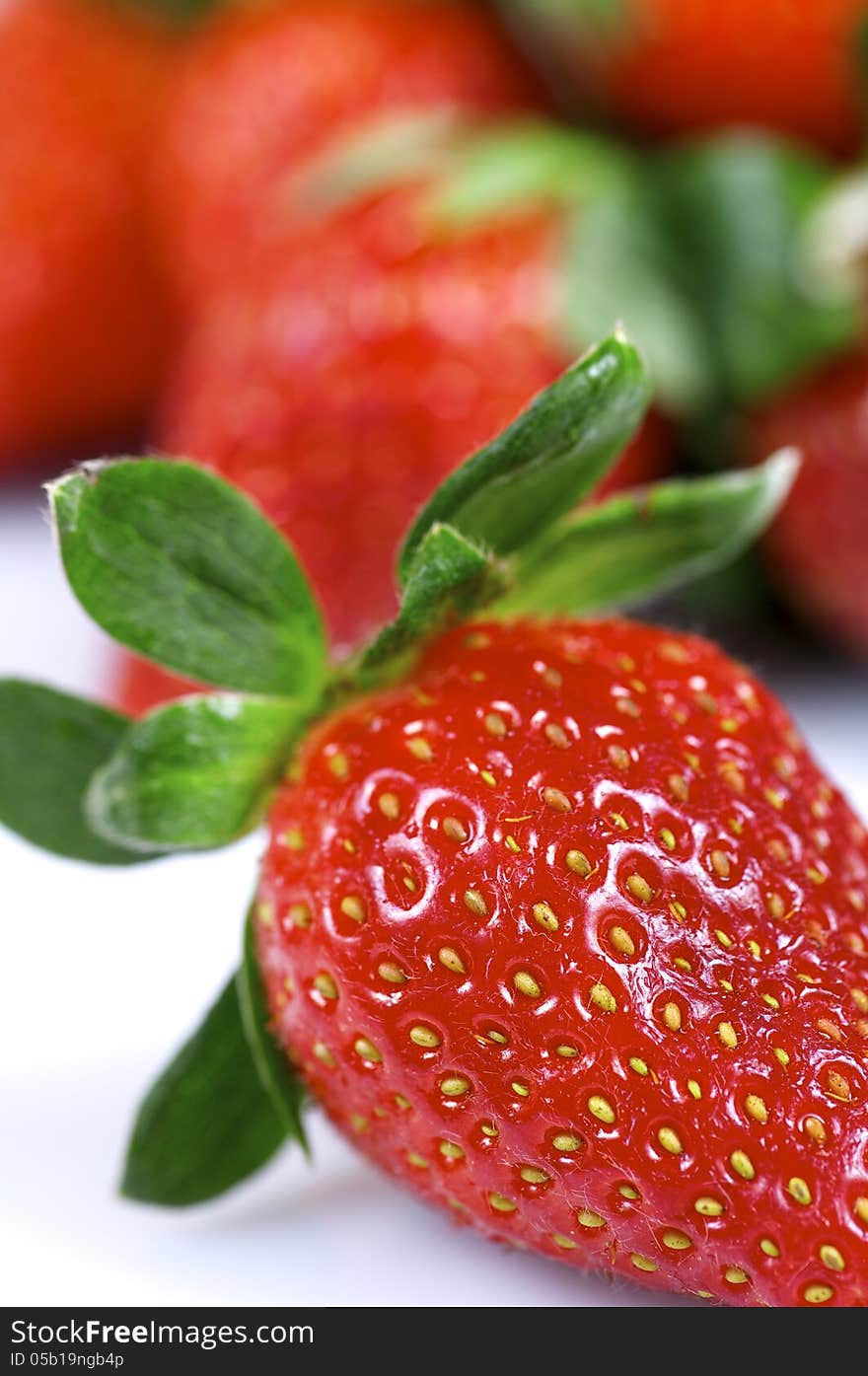 Forefront of a group of fresh strawberries on a white background