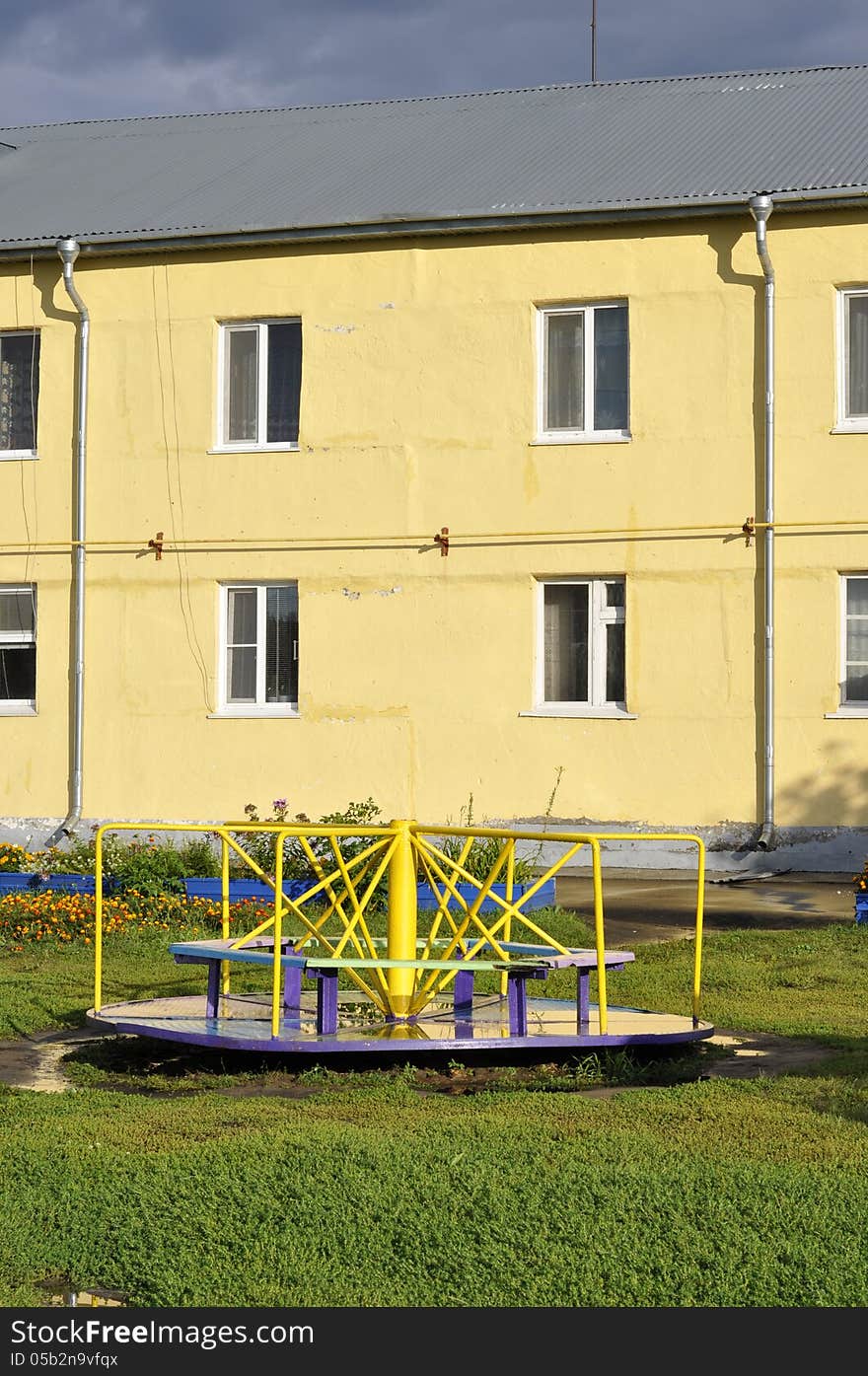 Children's Carousel on the background of the yellow house. Children's Carousel on the background of the yellow house.