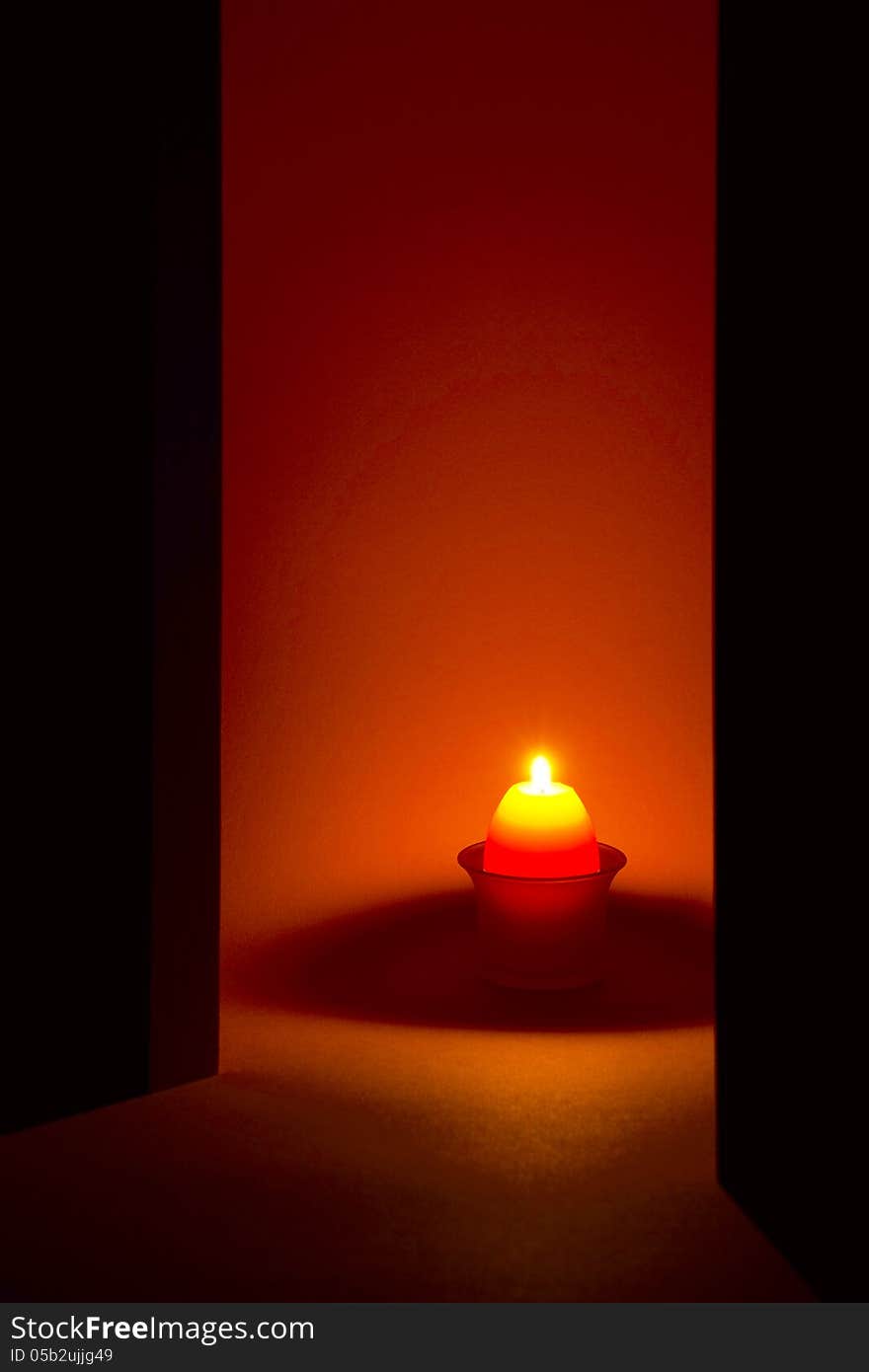 A candle in the shape of an egg in a glass candlestick, orange background. A candle in the shape of an egg in a glass candlestick, orange background