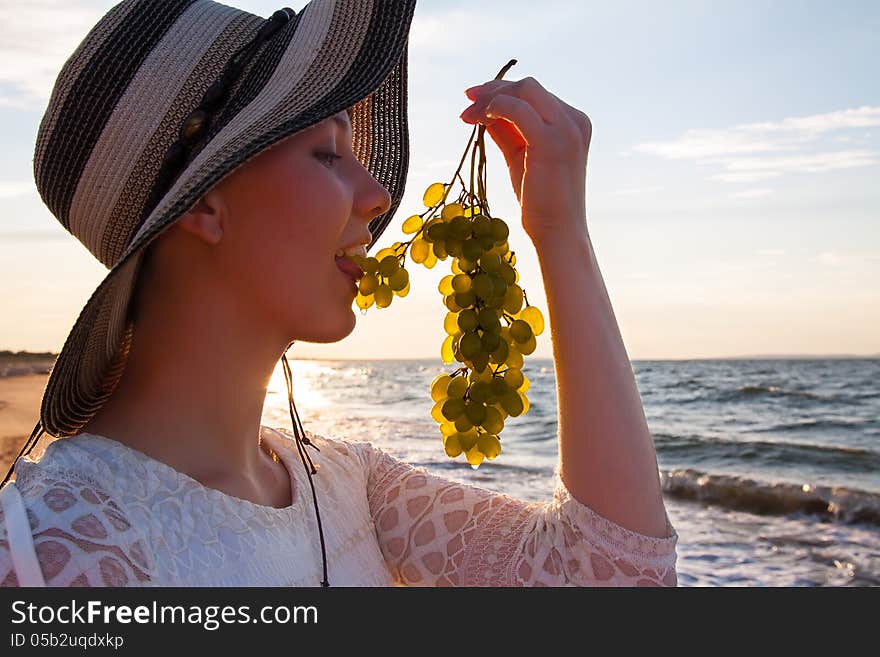 Portrait of sexy girl in hat holding grapes