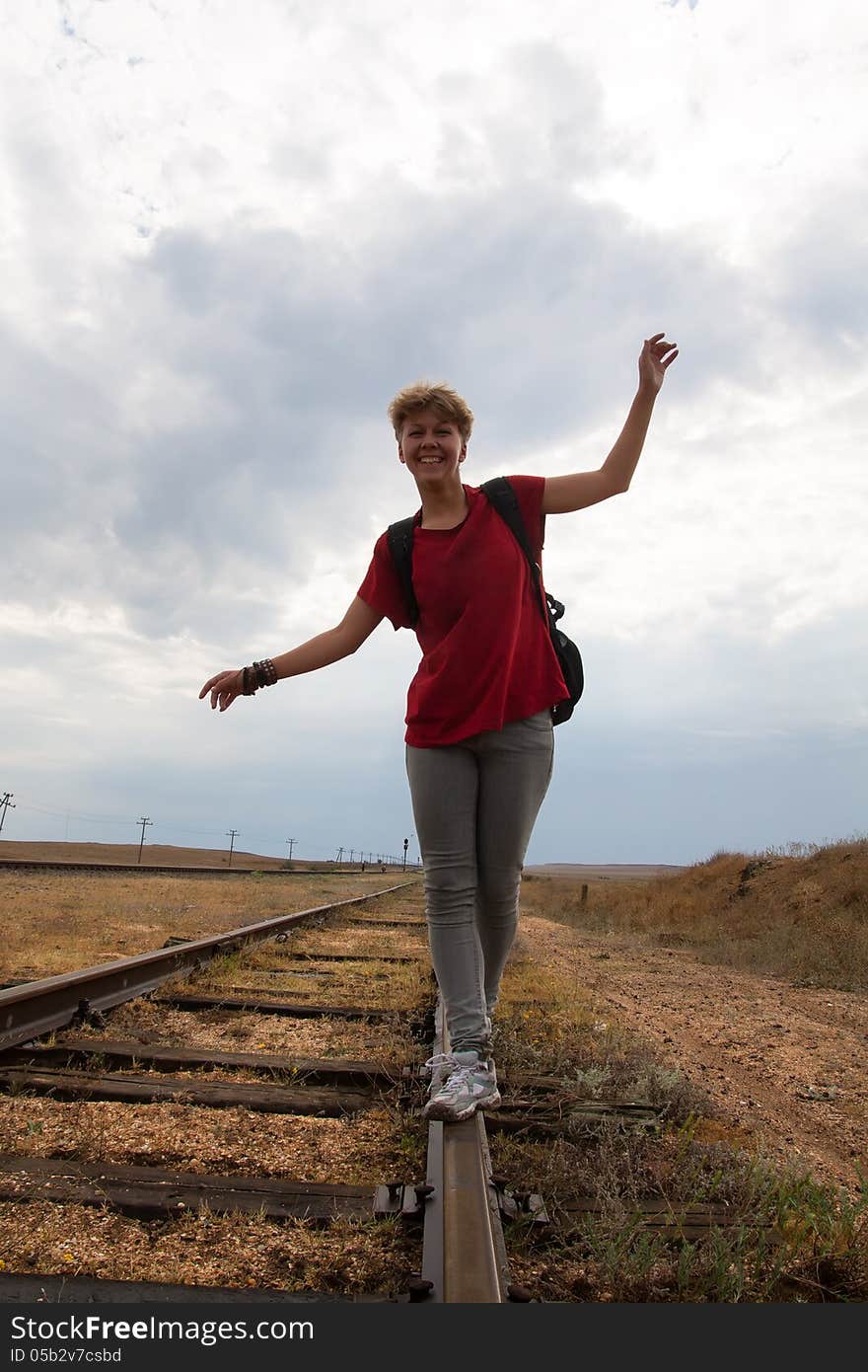 Smiling teen girl walking on rail road