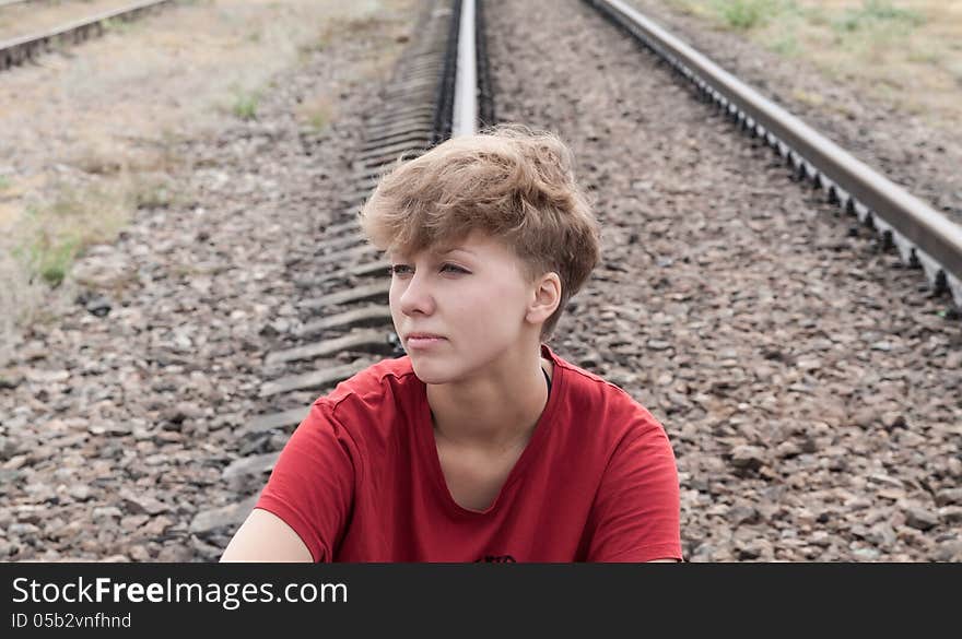 Sad teen girl sitting on rail road