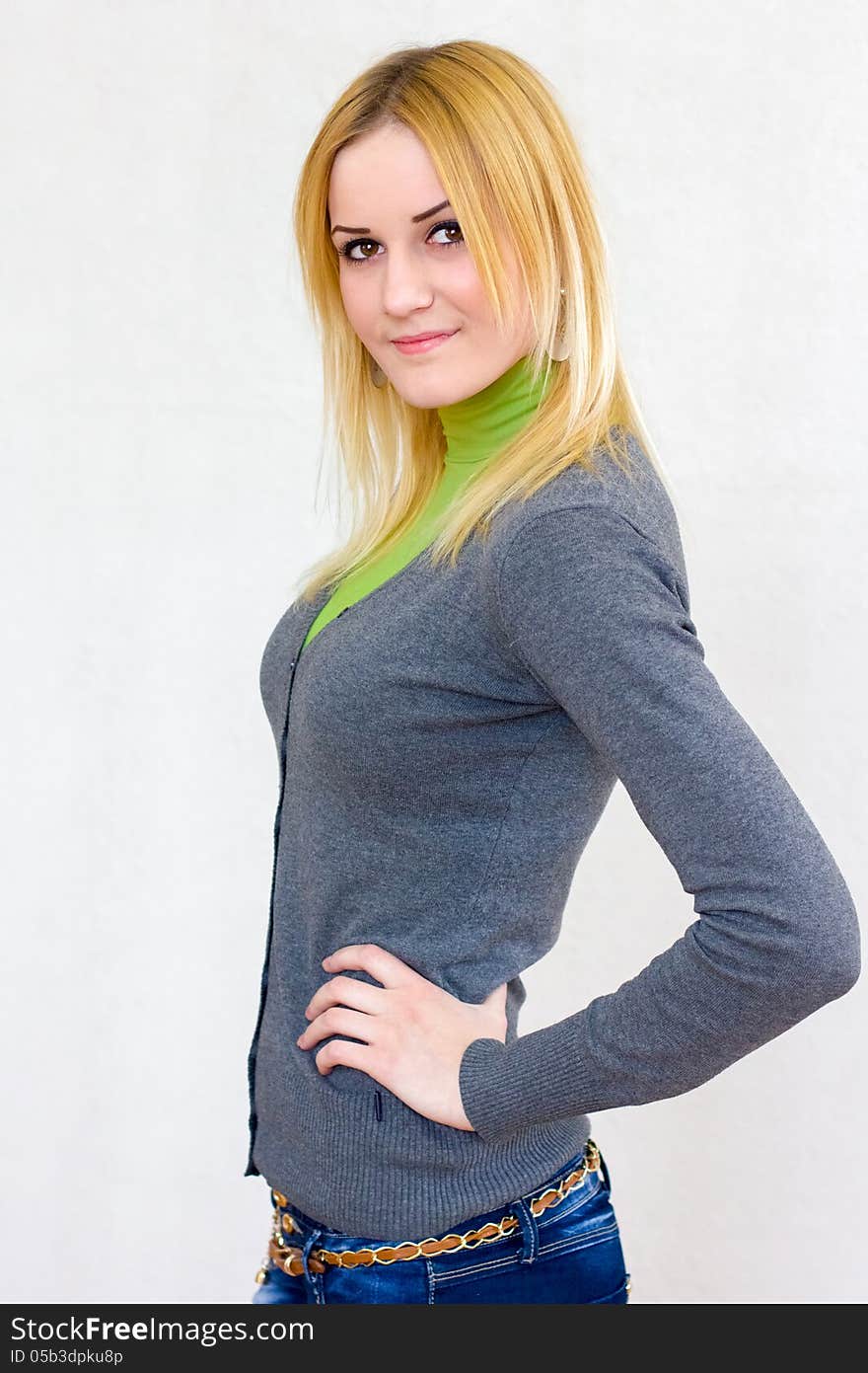 Portrait of a lovely blonde smiling girl with long hair in green turtleneck and gray cardigan