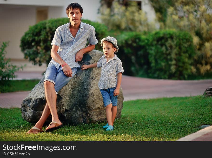 Summer's day father and son walking in the park near the big stone. Summer's day father and son walking in the park near the big stone