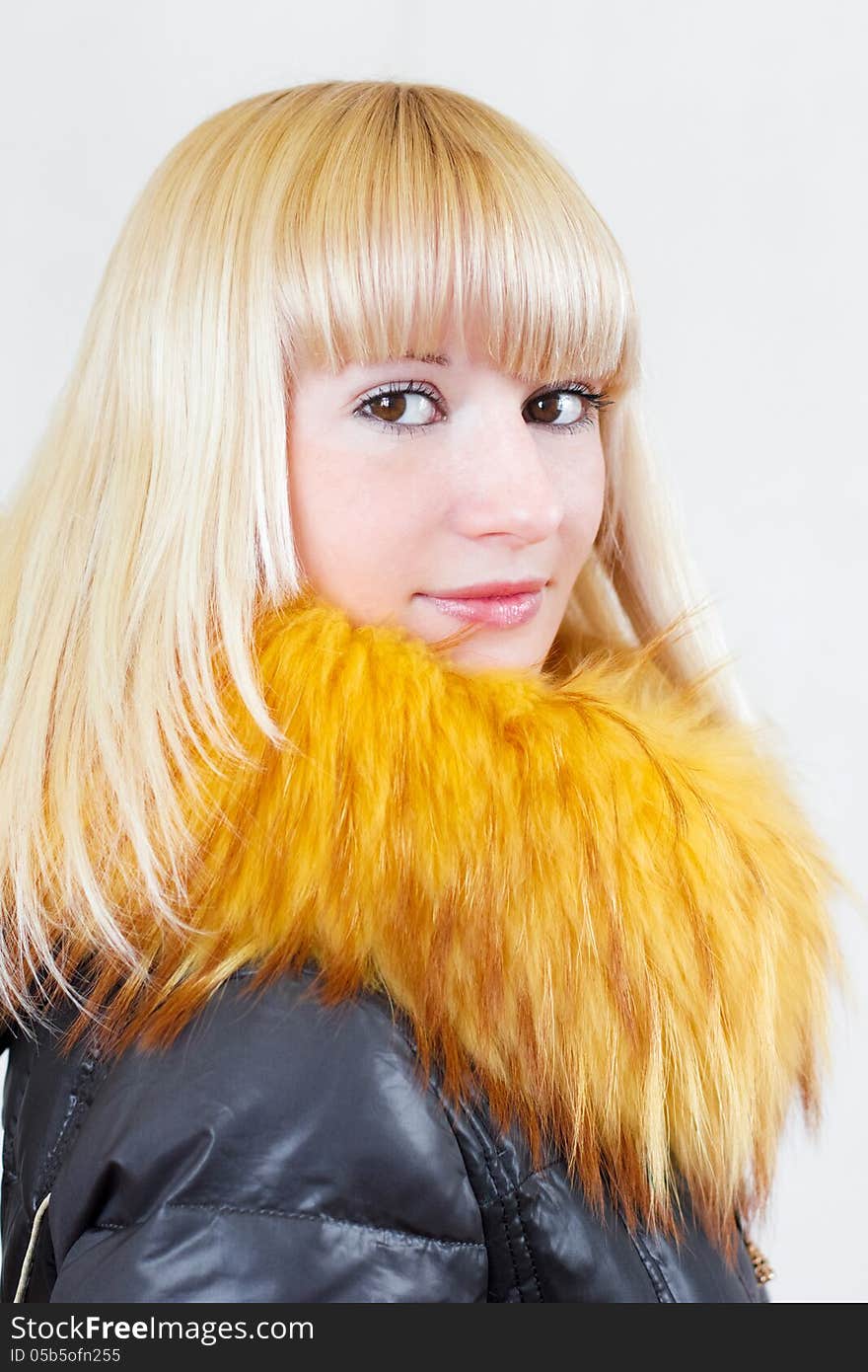 Close-up portrait of a lovely blonde serious girl with long hair in a leather jacket with fur collar