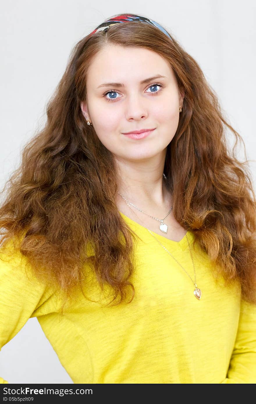 Portrait of a beautiful young cheerful brunette smiling girl with long red hair in the yellow blouse. Portrait of a beautiful young cheerful brunette smiling girl with long red hair in the yellow blouse