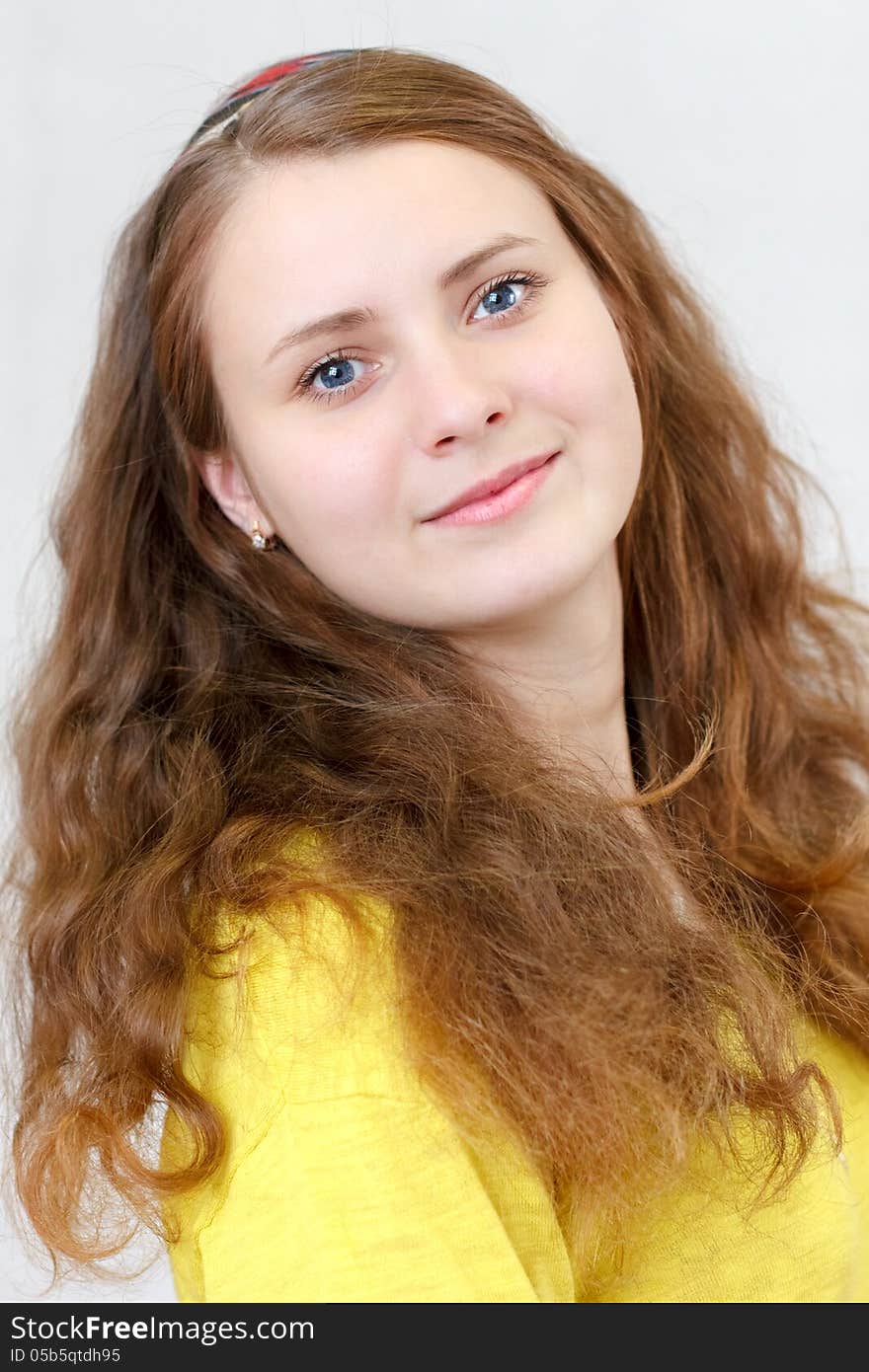 Portrait of a beautiful young cheerful brunette smiling girl with long red hair in the yellow blouse. Portrait of a beautiful young cheerful brunette smiling girl with long red hair in the yellow blouse