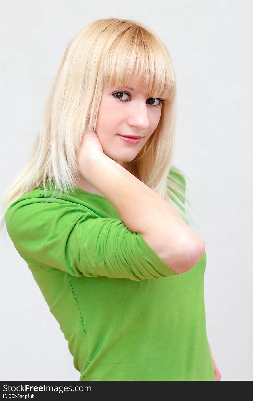 Close-up portrait of a lovely blonde smiling girl with long hair in the green shirt