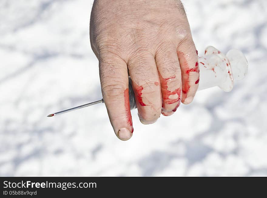 Bloody hand holding syringes