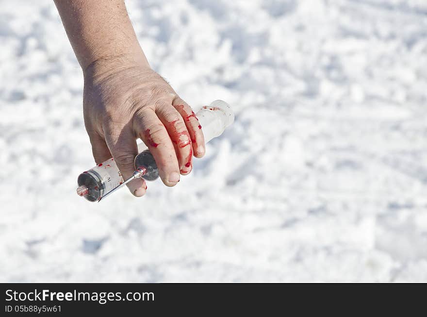 Bloody hand holding syringe