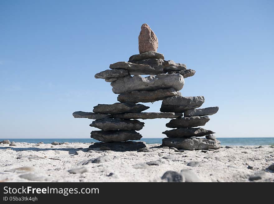 Inukshuk resting on the shoreline with blue sky copy space area