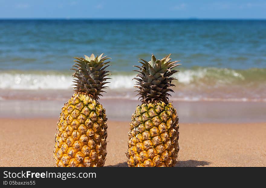 Two pineapples on the beach.