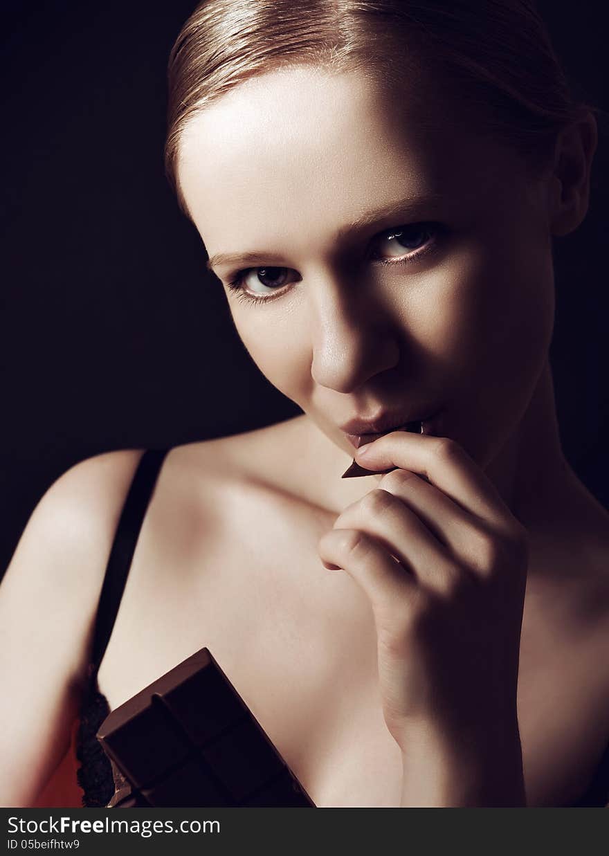 Sexy Beautiful Young Woman Eating Chocolate On A Dark