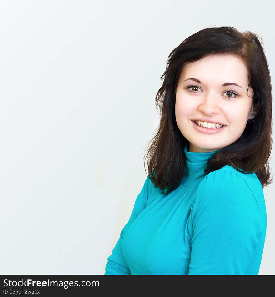 Close-up portrait of a beautiful happy young cheerful brunette smiling girl in the blue sweater. Close-up portrait of a beautiful happy young cheerful brunette smiling girl in the blue sweater