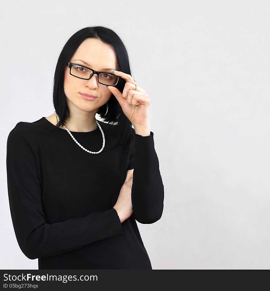 Serious brunette girl in a black dress and sunglasses with a short haircut calm strictly looking at the camera. Serious brunette girl in a black dress and sunglasses with a short haircut calm strictly looking at the camera