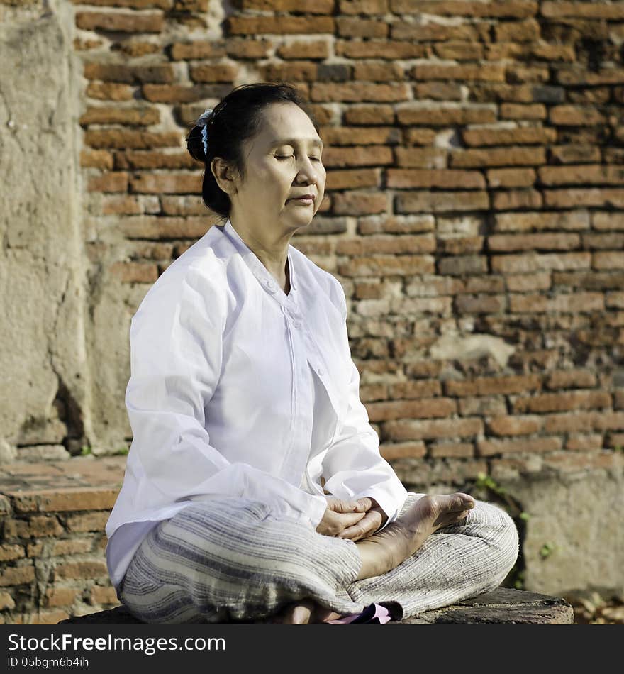 Woman meditating against ancient temple