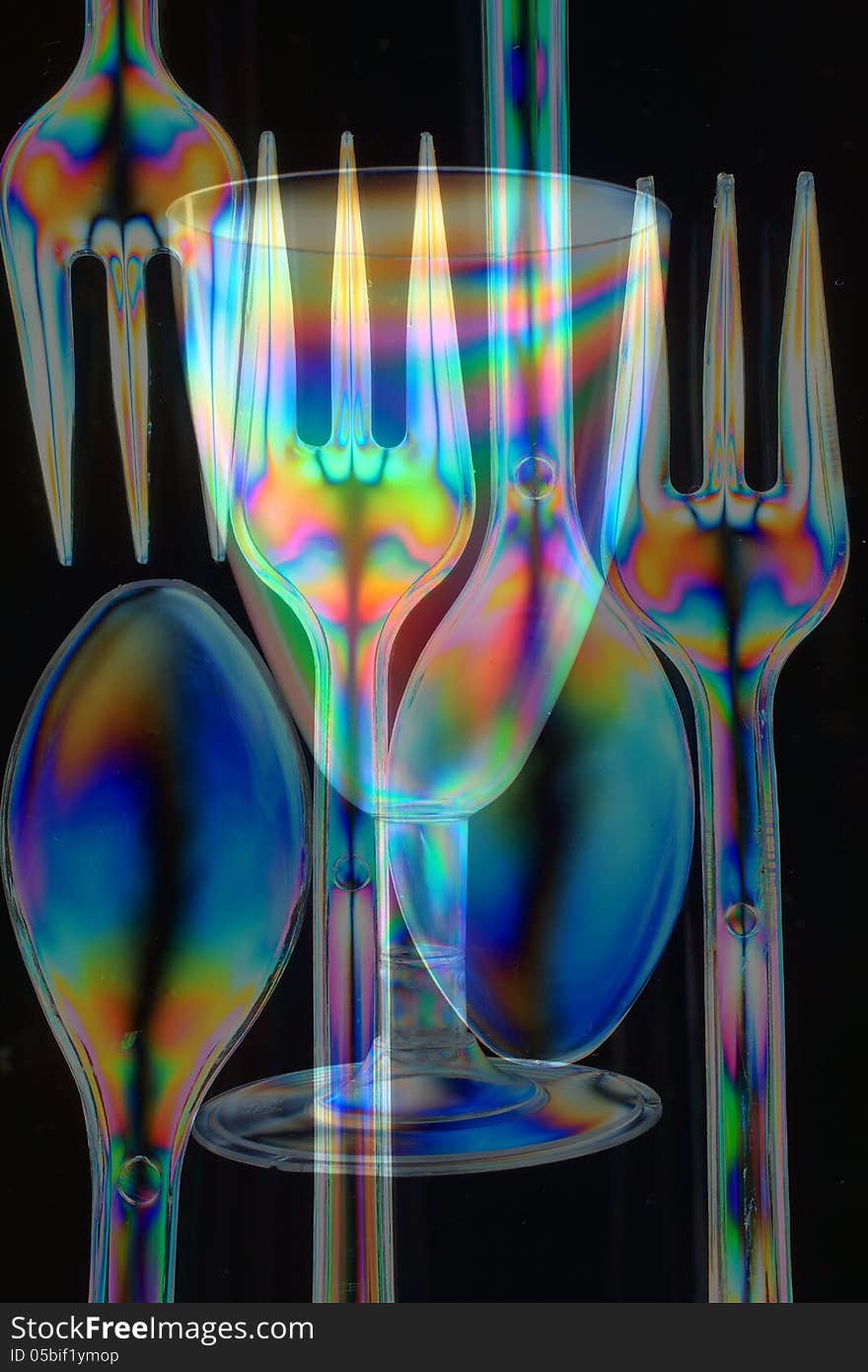 Spoons, forks and partybeaker consisting of transparent plastic, seen in polarized light, composed together. Spoons, forks and partybeaker consisting of transparent plastic, seen in polarized light, composed together