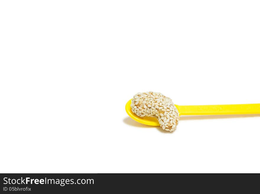 Sweet cashew nut with sesame on yellow spoon