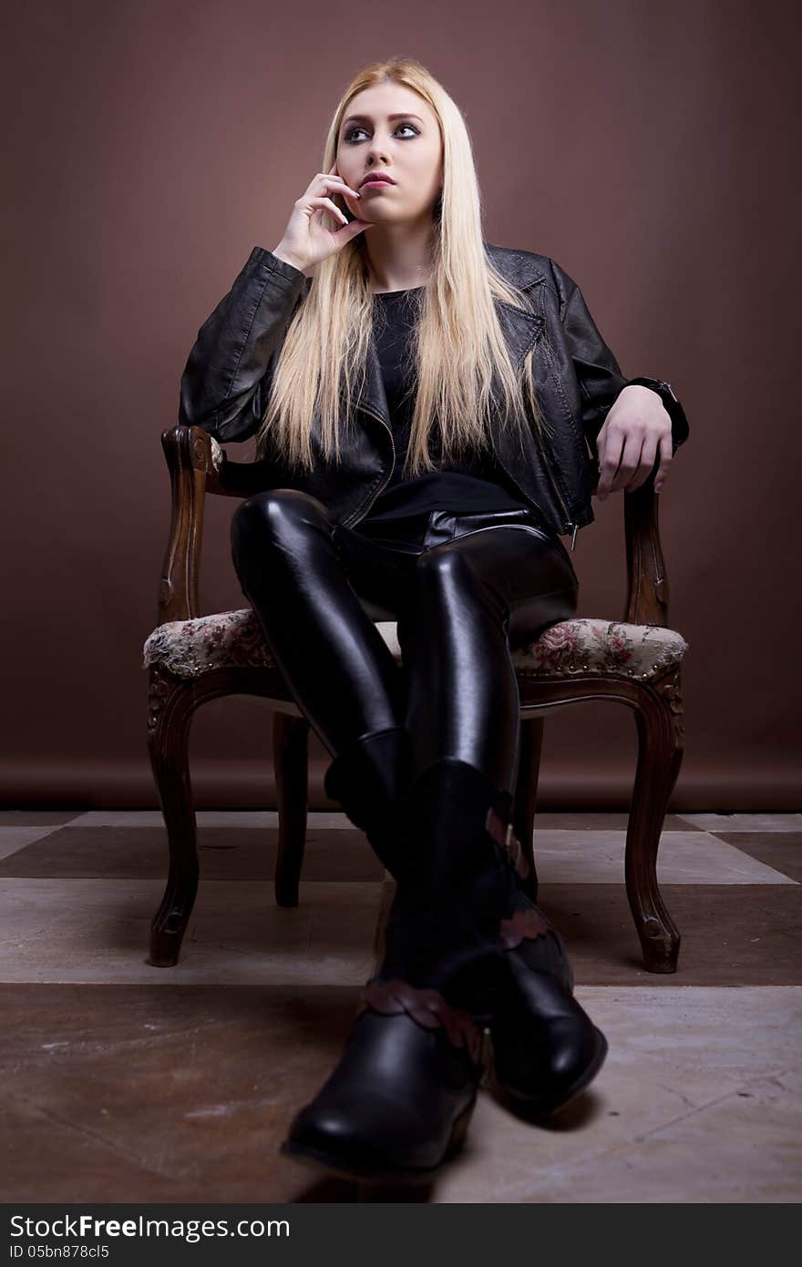 Rocker girl on a vintage chair on brown background