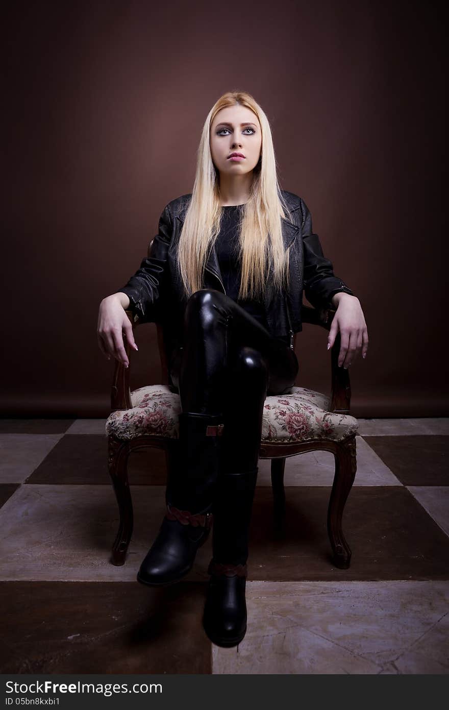 Gorgeous rock girl sitting on a vintage chari full body studio shot