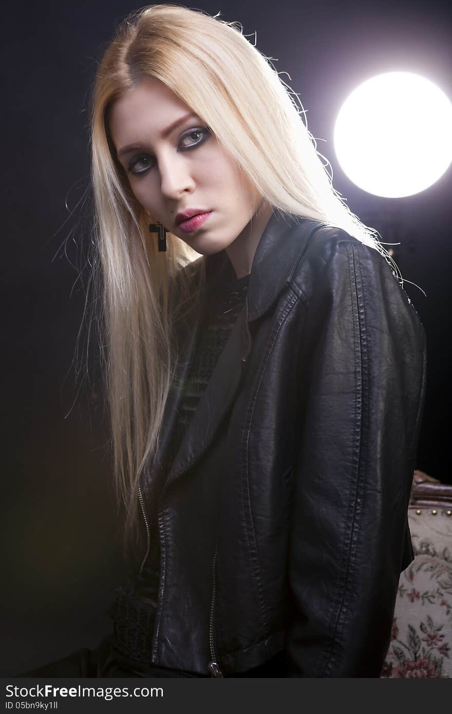 Artistic portrait of a girl in leather jacket with a light behin