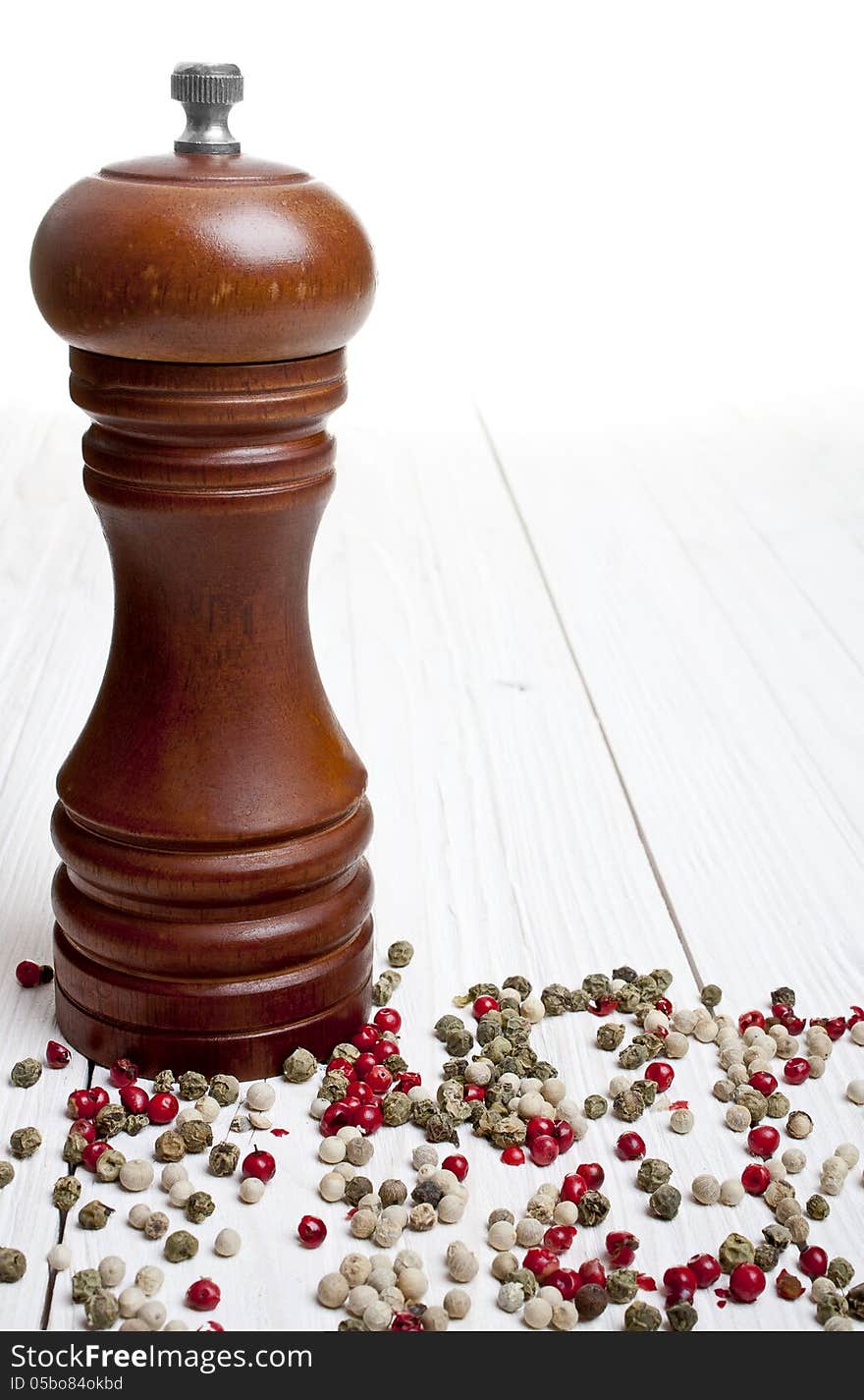 Pepper-mill with peppercorns on white background