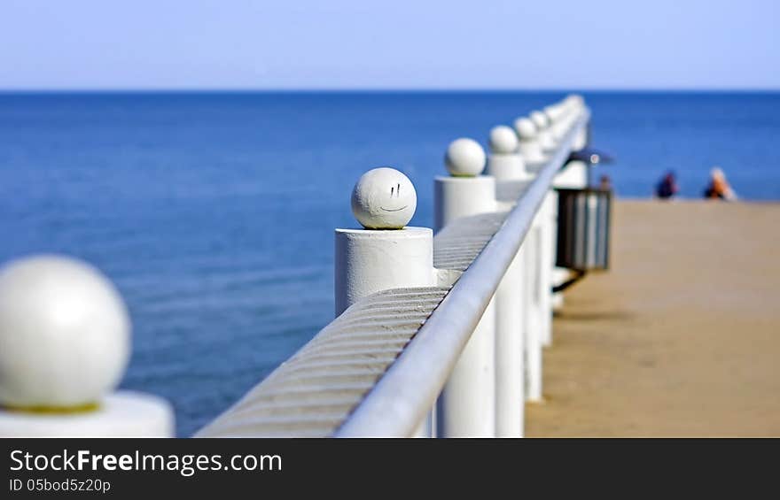 Sea pier railing with a painted smiley