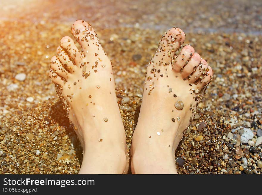 Girl`s barefoot legs in the sand