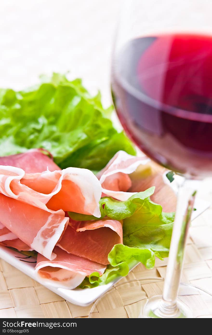 Glass with red wine and ham with salad