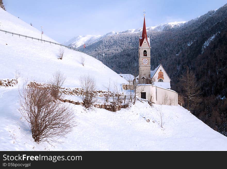 A wintertime view of a small church with a tall steeple