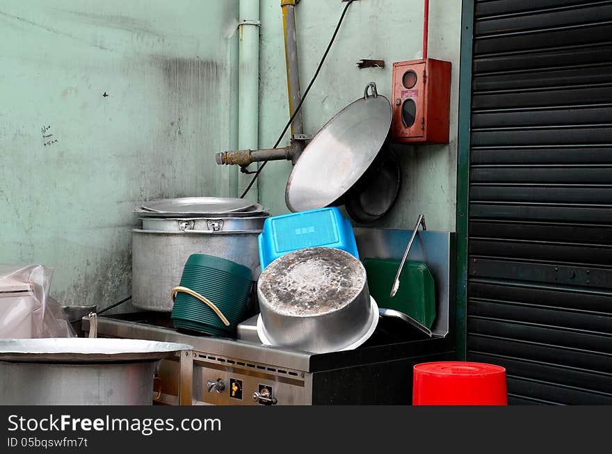 A pile of clean pots, pans and other dishes rest on an outdoor sink. Scene located in a mosque in Singapore. A pile of clean pots, pans and other dishes rest on an outdoor sink. Scene located in a mosque in Singapore.