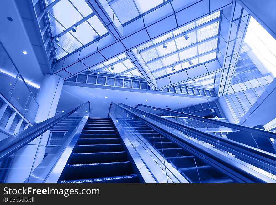 Escalator in modern business center. Blue toning image