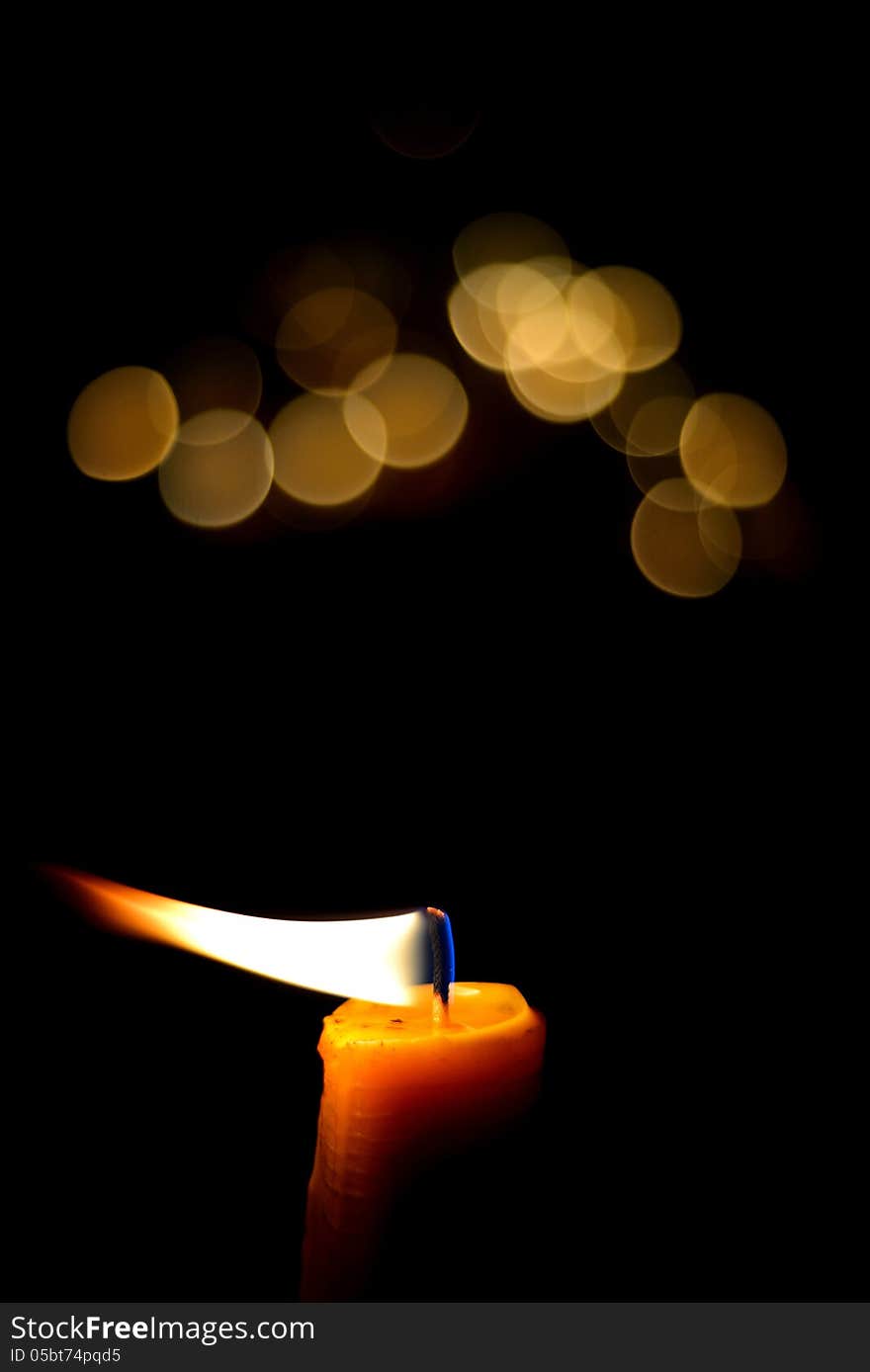 One candle flame at night with bokeh