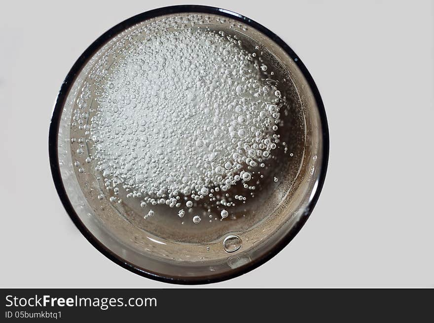 An effervescent pill of magnesium fizzing in a glass of water - seen from above. An effervescent pill of magnesium fizzing in a glass of water - seen from above.