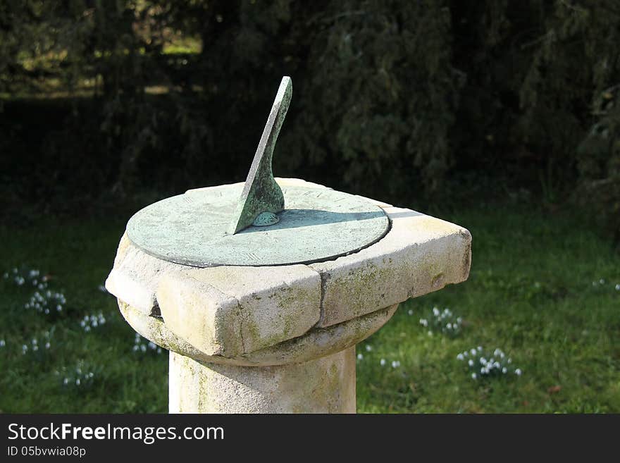 A Traditional Metal Sun Dial Standing on a Stone Plinth. A Traditional Metal Sun Dial Standing on a Stone Plinth.