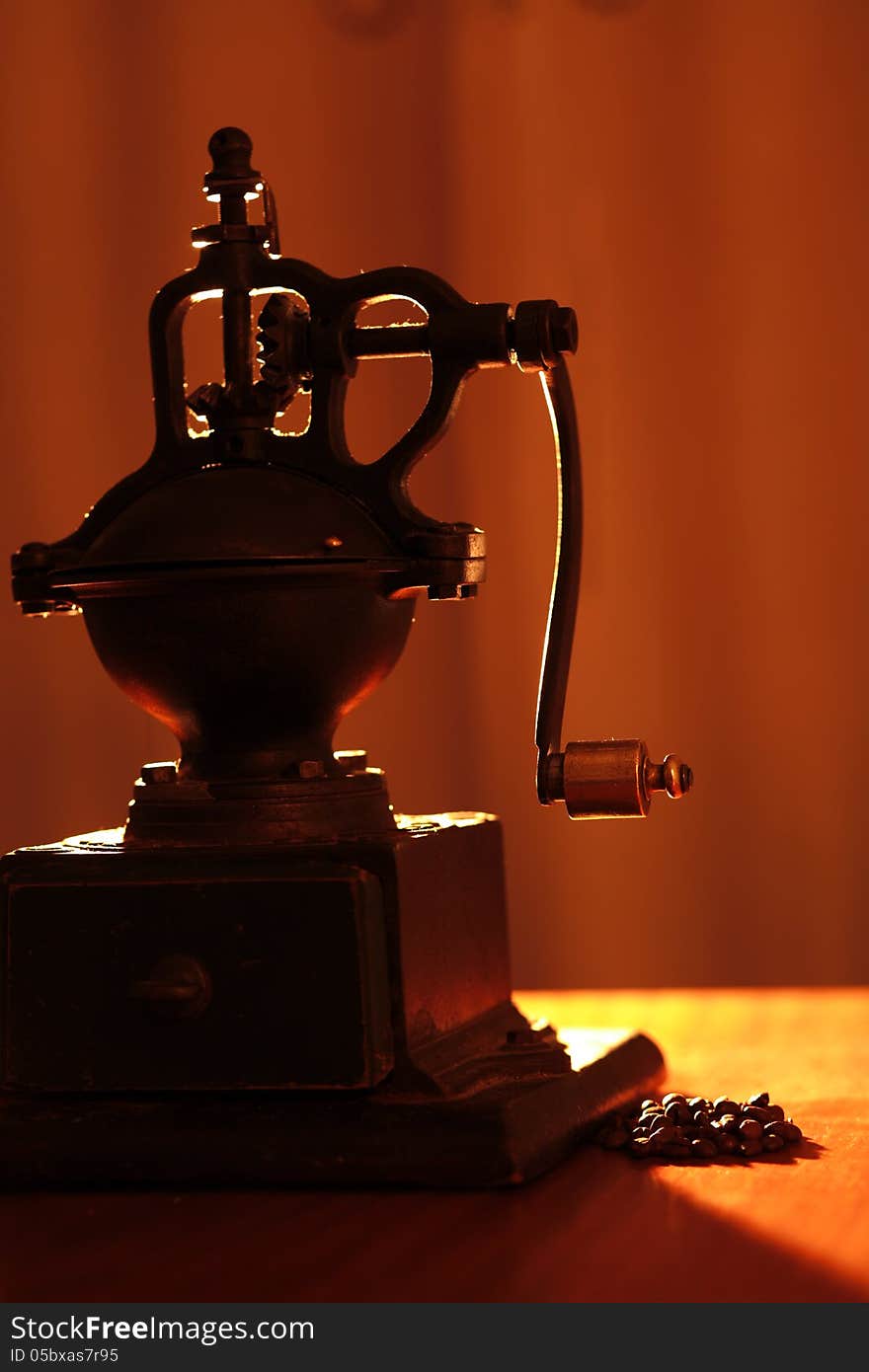 An old coffe grinder with back light and some coffee beans. An old coffe grinder with back light and some coffee beans.