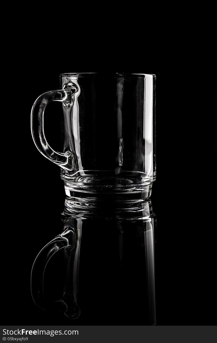 Empty glassware cup on reflecting surface. on black background. Shot in studio. Empty glassware cup on reflecting surface. on black background. Shot in studio.