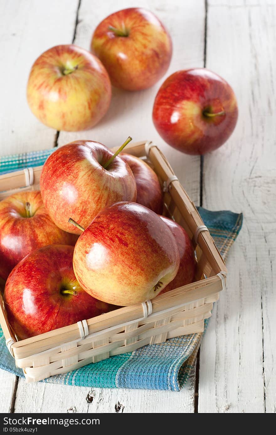 Several of red apples in wicker basket on the white kitchen table