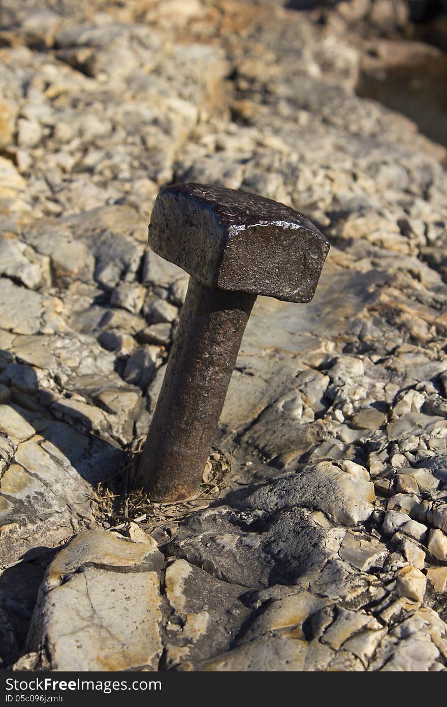 Abstract view of a weathered bolt hammered into the limestone many years ago. The bolt is smooth with age and wear but still strong. Abstract view of a weathered bolt hammered into the limestone many years ago. The bolt is smooth with age and wear but still strong.