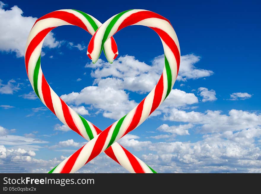 Heart of two sugar sticks on background of sky and clouds