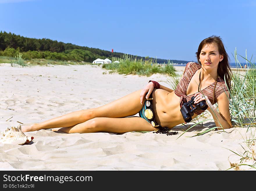 Young woman with field-glass on a beach.