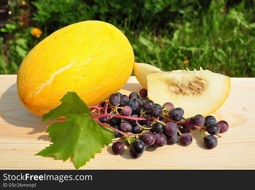 Melon and grapes on a wooden plank. Melon and grapes on a wooden plank.