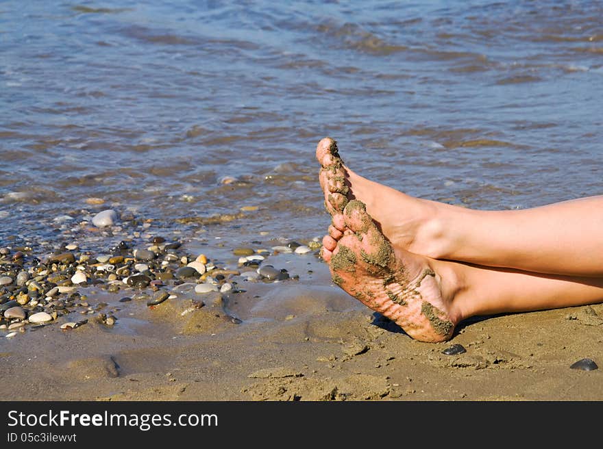 Female legs on the sand by the sea