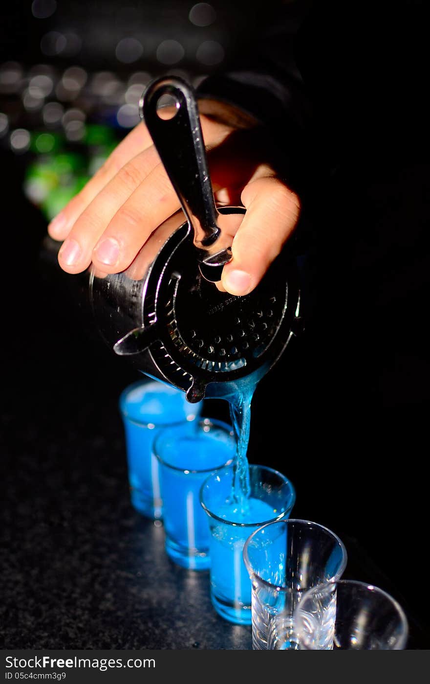 Bartender pours shoots in glasses