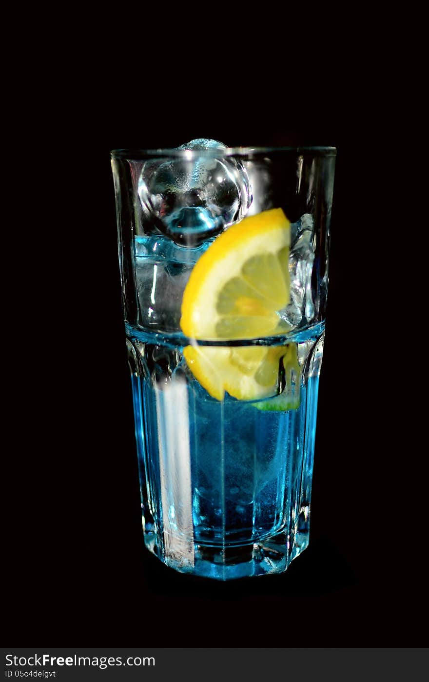 A blue drink in tall glass with lemon and ice